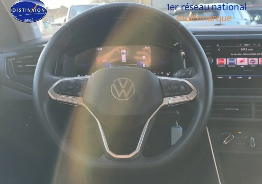 Vue intérieure centrée sur le volant cuir multifonction d'une Volkswagen Polo gris, avec tableau de bord et écran tactile visibles.