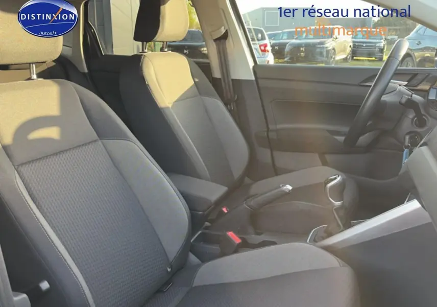 Vue intérieure côté droit de la Volkswagen Polo gris, montrant les sièges avant et la console centrale avec levier de vitesse manuel.