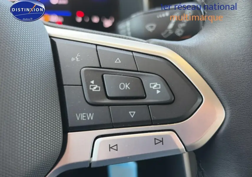 Gros plan sur les commandes multifonctions du volant cuir de la Volkswagen Polo gris, avec boutons de navigation et audio.