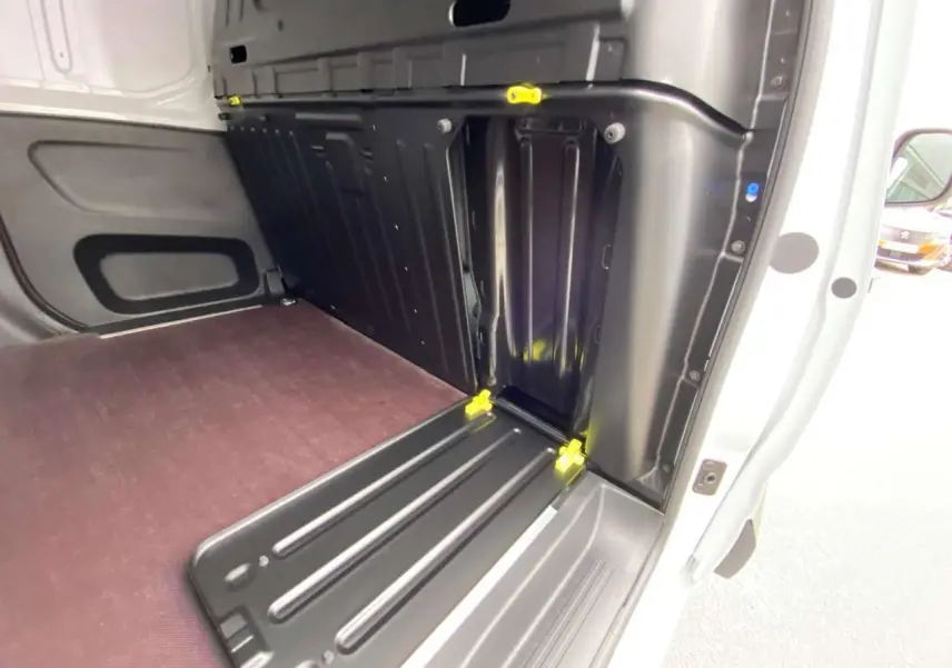 Vue intérieure du compartiment de chargement arrière droit du Citroën Berlingo blanc avec plancher bois et renforts noirs.