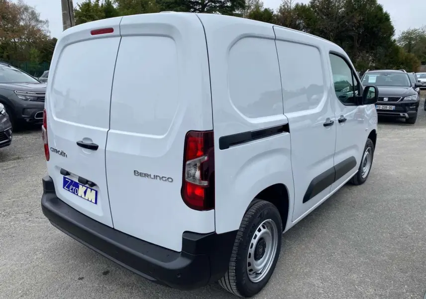Vue 3/4 arrière droite d’un utilitaire Citroën Berlingo blanc avec protections latérales noires et porte arrière fermée.