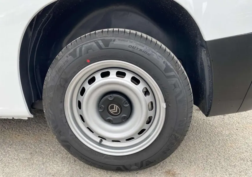 Gros plan sur la roue arrière droite d’un Citroën Berlingo blanc avec jante acier grise et logo Citroën central.