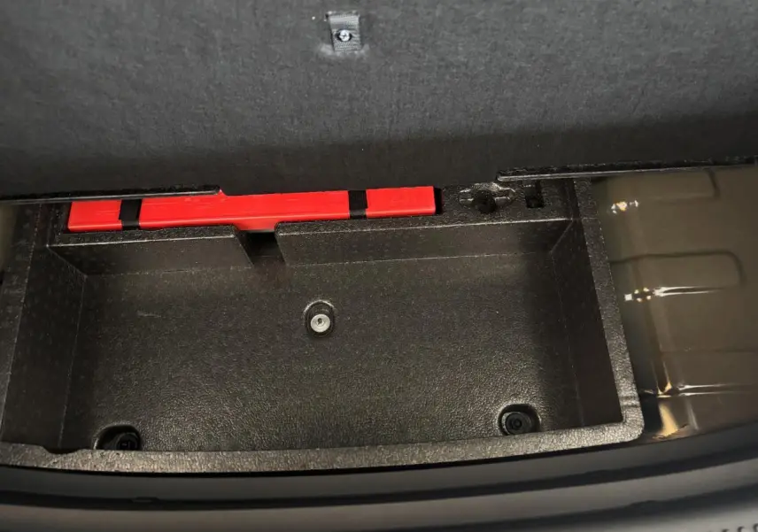 Coffre de rangement noir ouvert dans le coffre arrière du MG Motor ZS 1.5 Hybrid+ Luxury 2026, avec un triangle de signalisation rouge visible.