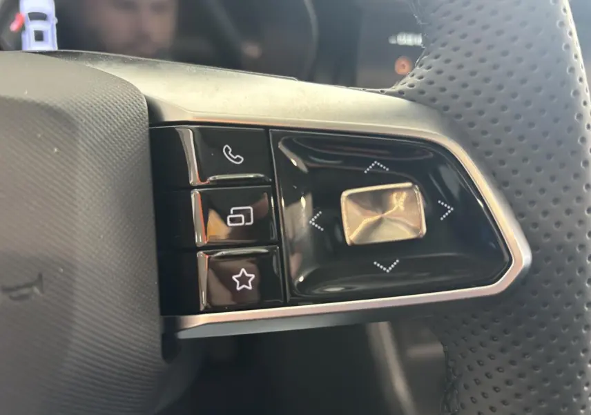 Gros plan sur les commandes gauche du volant perforé du MG Motor ZS 1.5 Hybrid+ noir, boutons lumineux.