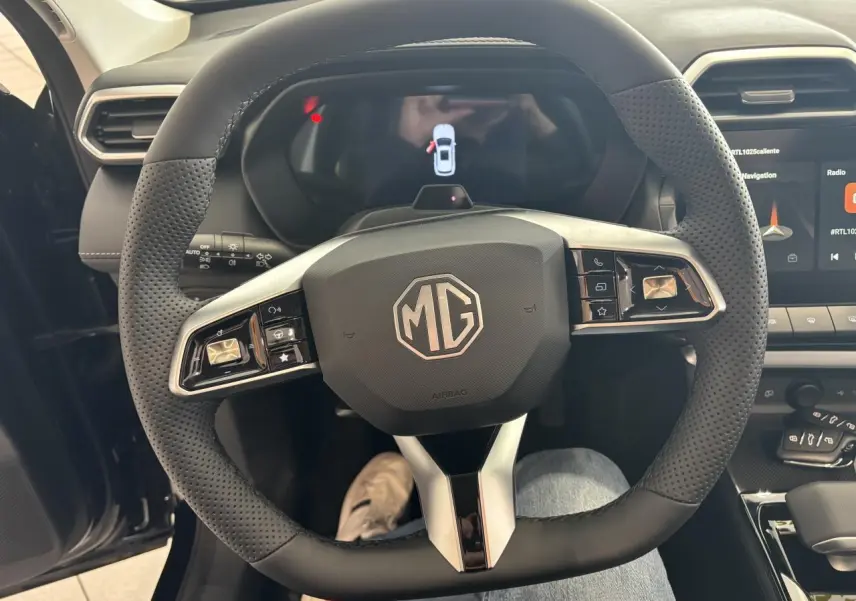 Vue rapprochée du volant noir perforé de la MG ZS 1.5 Hybrid+ 2026 avec commandes intégrées et tableau de bord numérique.
