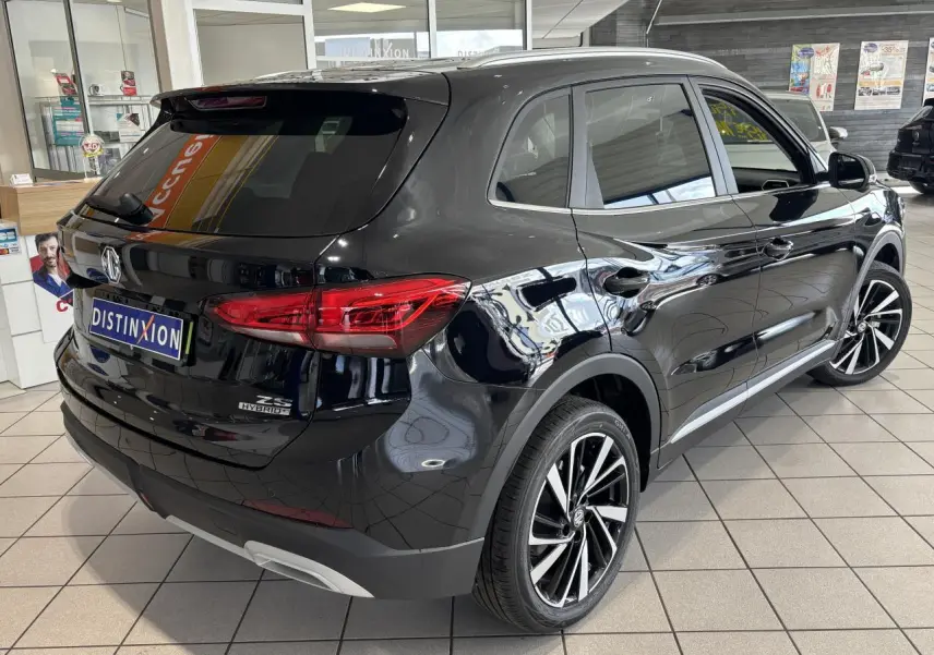 Vue 3/4 arrière droite du MG ZS Hybrid+ noir avec jantes alliage 18 pouces et vitres surteintées en showroom.