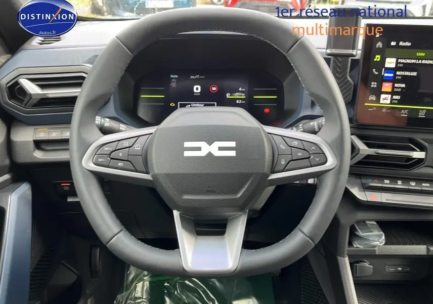 Vue intérieure centrée sur le volant multifonction du Dacia Duster gris schiste 2025 avec tableau de bord numérique et écran tactile.