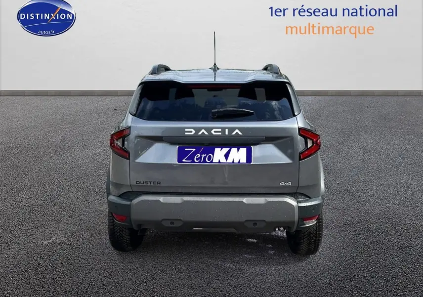 Vue arrière du Dacia Duster gris schiste 2025 avec logo DACIA et plaques Zero KM visibles sur un sol goudronné.