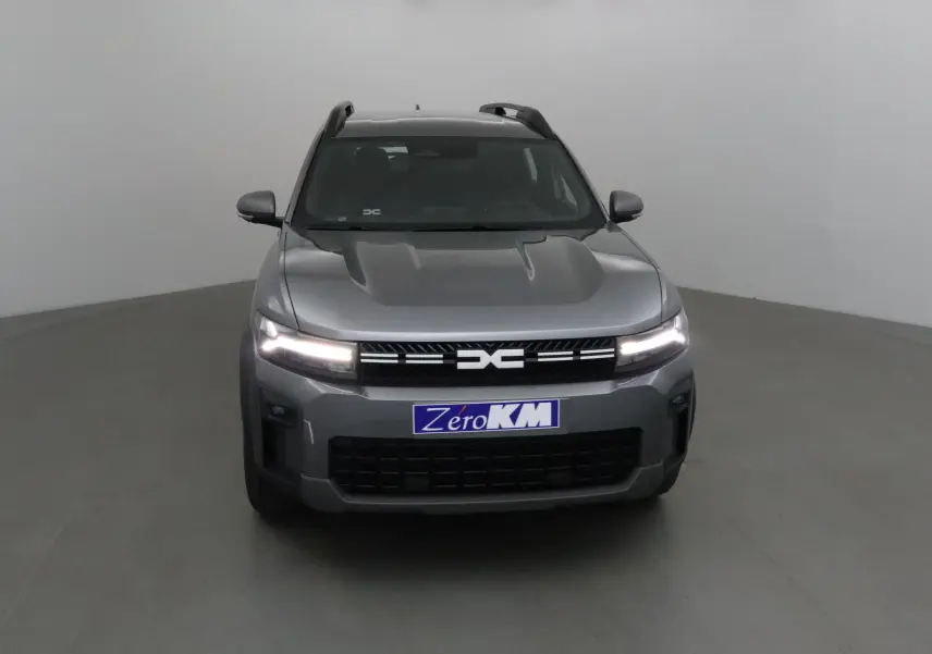 Vue frontale du Dacia Bigster gris schiste avec calandre noire et feux LED allumés dans un studio.