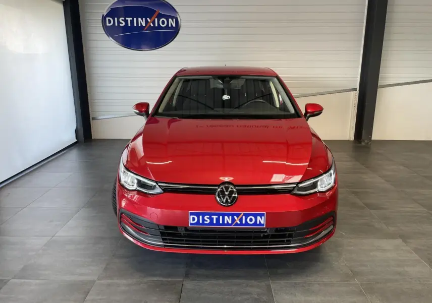 Volkswagen Golf 8 Active rouge métal vue de face en intérieur avec logo Distinxion visible.