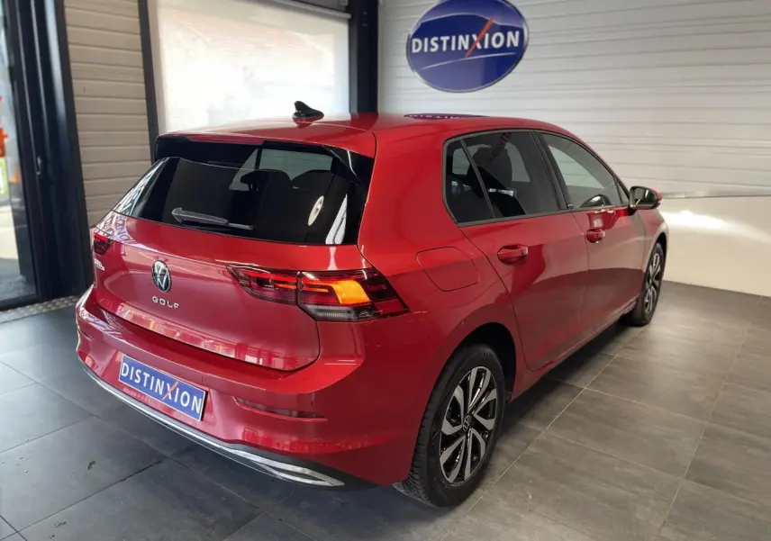 Volkswagen Golf rouge métallisé vue 3/4 arrière droit en intérieur avec jantes alliage distinctives