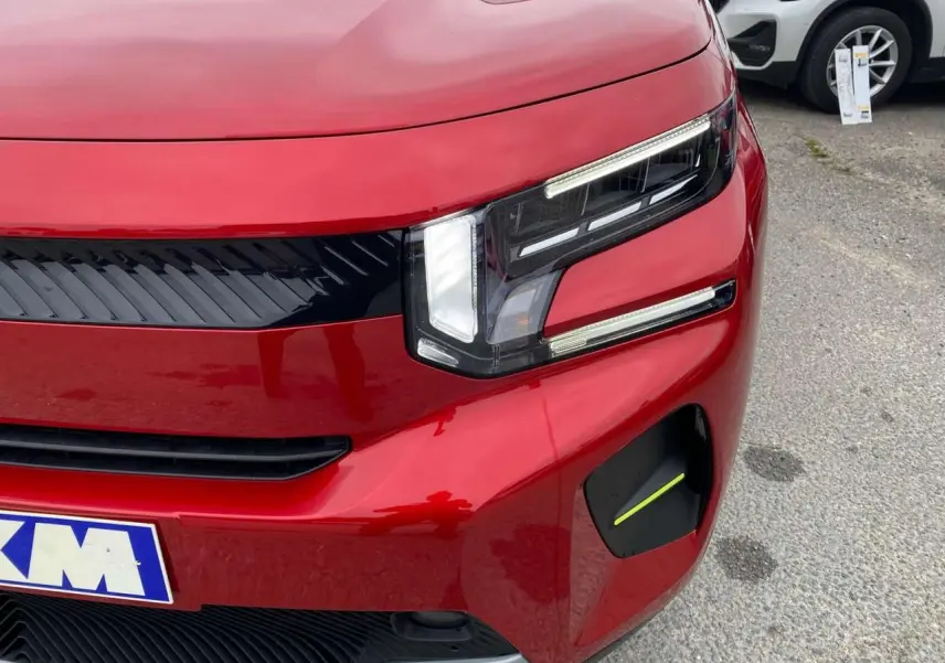 Gros plan sur l'avant droit d'une Citroën C3 rouge Elixir avec toit noir, mettant en valeur son phare LED distinctif.