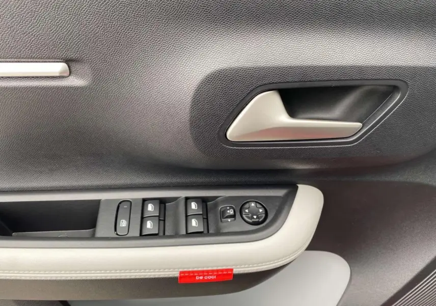 Gros plan sur la poignée intérieure et les commandes des vitres côté conducteur de la Citroën C3 rouge Elixir toit noir.