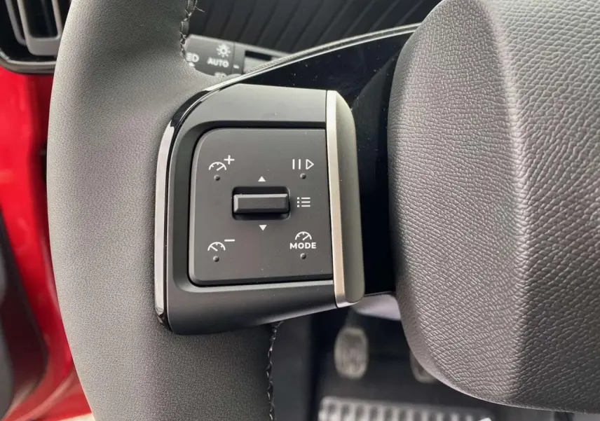 Détail du bouton de commande du régulateur de vitesse sur le volant d'une Citroën C3 rouge Elixir avec toit noir.