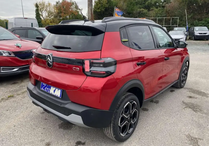 Vue 3/4 arrière droite d'une Citroën C3 rouge Elixir au toit noir avec jantes alliage et vitres arrière surteintées.