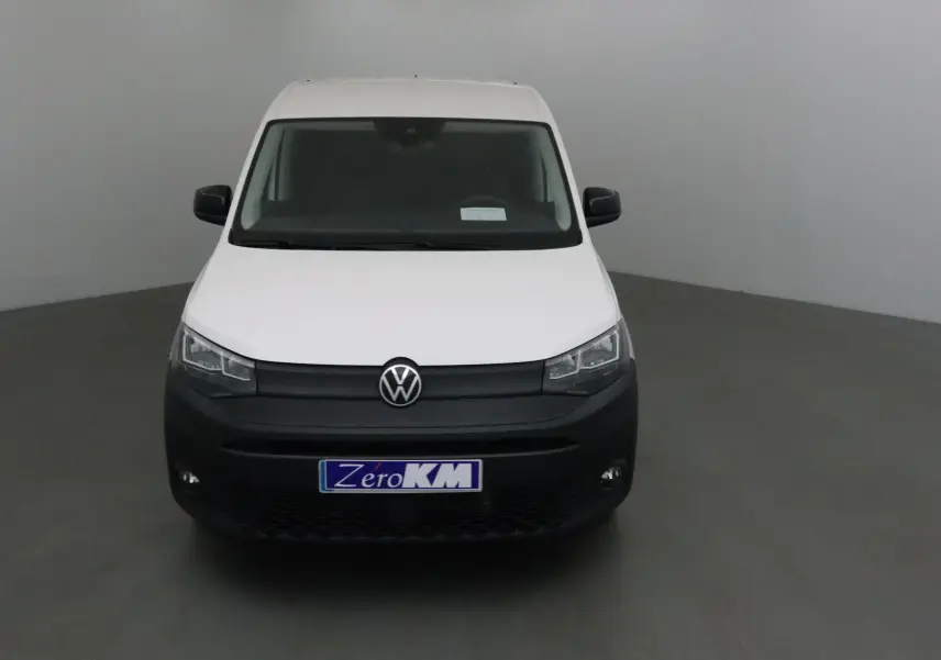 Vue frontale d'un Volkswagen Caddy Maxi blanc avec pare-chocs noir et plaque "Zero KM" visible.