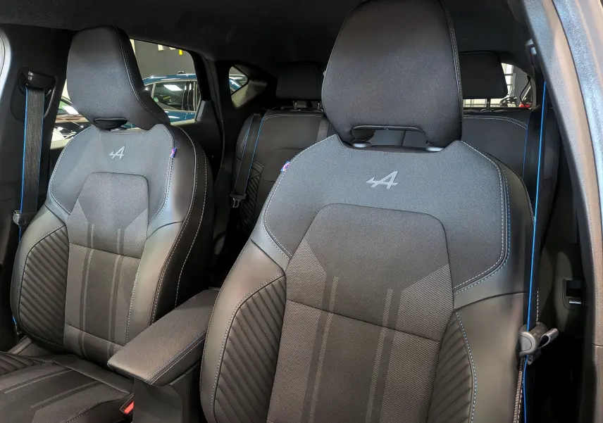 Gros plan sur les sièges avant noirs avec surpiqûres bleues et logo Alpine du Renault Captur E-TECH 2025.