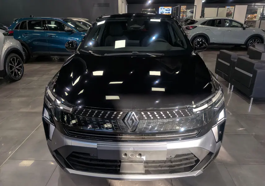 Vue avant rapprochée du Renault Captur E-Tech 2025 noir étoilé, soulignant sa calandre lumineuse et son logo central.