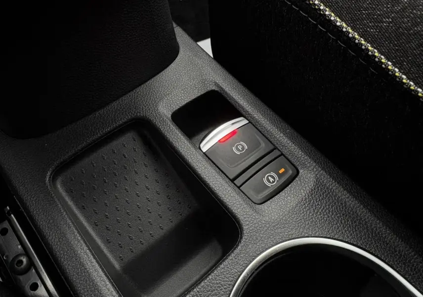 Gros plan sur la console centrale noire du Renault Captur 2025, avec frein à main électrique et bouton auto-hold.