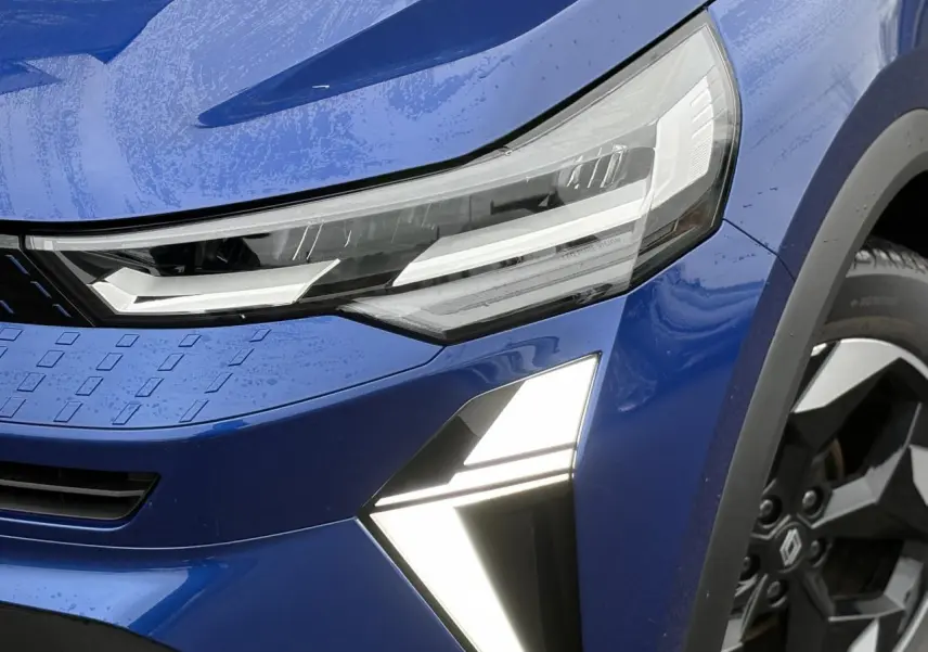 Gros plan sur l'avant droit du Renault Captur Bleu Iron, mettant en valeur les phares LED et la jante aluminium 18 pouces.