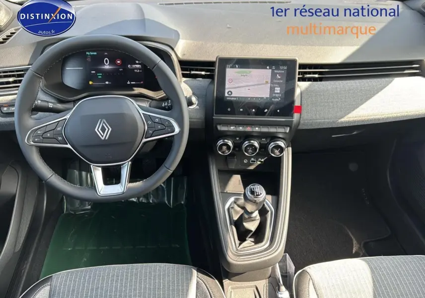 Vue intérieure avant de la Renault Clio V noire, volant multifonction, écran tactile et levier de vitesse manuel visibles.
