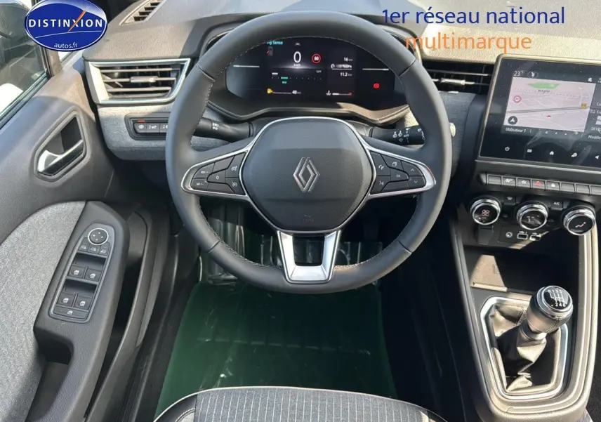 Vue intérieure frontale du poste de conduite de la Renault Clio V avec volant multifonction et écran tactile central.