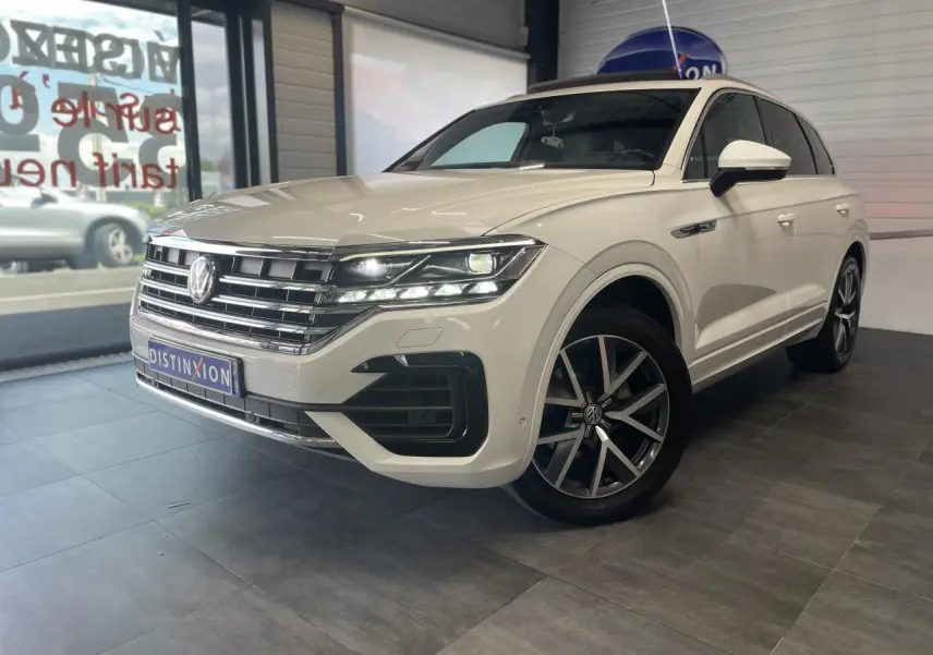 Volkswagen Touareg blanc en 3/4 avant droit avec jantes alliage 20 pouces et calandre chromée showroom intérieur.