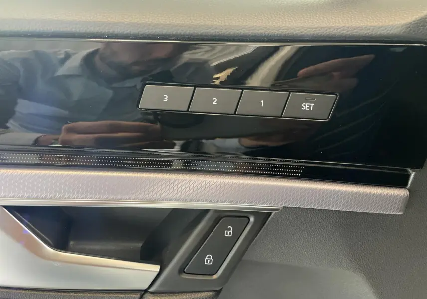Détail intérieur montrant les boutons de mémorisation des sièges et les commandes de verrouillage sur la porte côté conducteur.