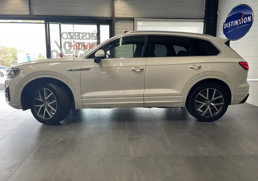 Vue de profil côté gauche d’un Volkswagen Touareg blanc 2019 avec jantes alliage 20 pouces et vitres sur-teintées.