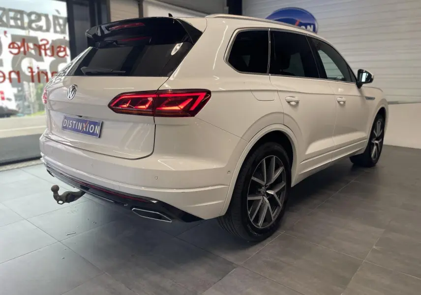 Vue 3/4 arrière droite du Volkswagen Touareg blanc avec jantes alliage 20 pouces et feux arrière LED allumés.