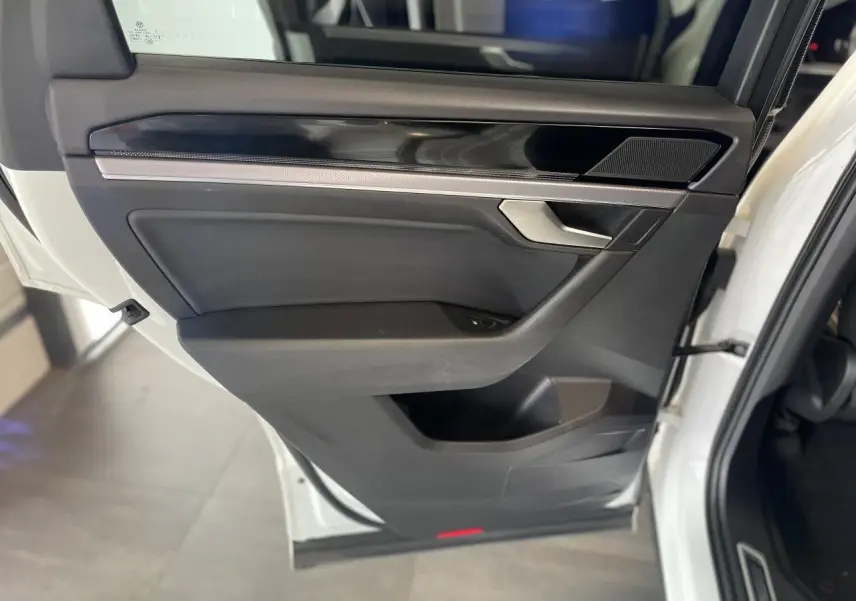 Vue intérieure côté gauche de la porte arrière blanche du Volkswagen Touareg 2019 avec garniture noire et insert laqué piano.