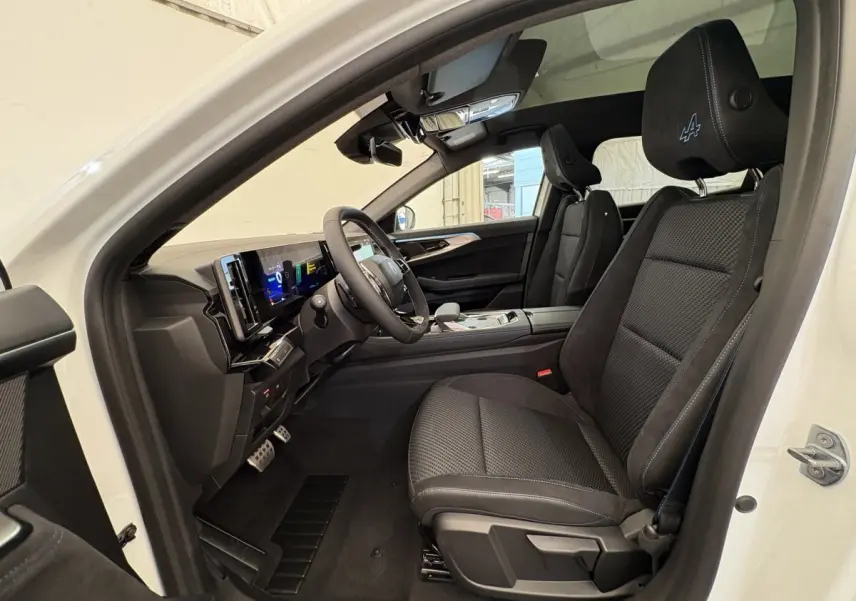 Vue intérieure côté conducteur du Renault Espace blanc 2025, sièges noirs avec logo Alpine brodé sur appuie-tête.