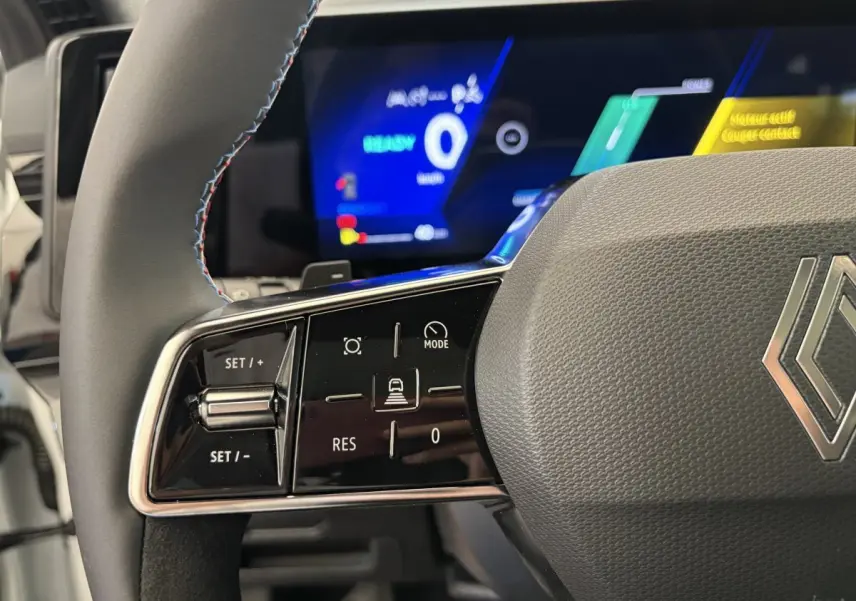 Gros plan sur le volant cuir et suède avec commandes multifonctions du Renault Espace blanc, tableau de bord numérique en arrière-plan.