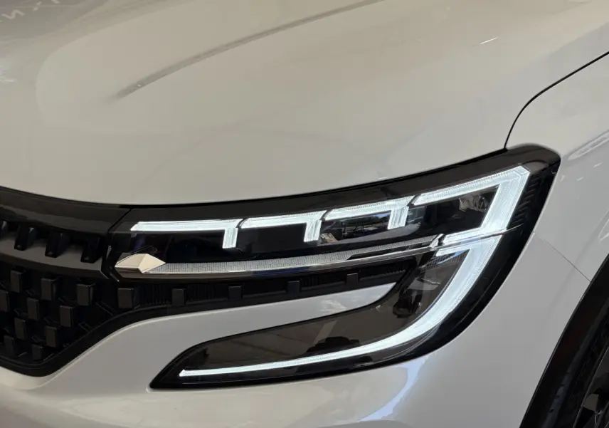 Gros plan sur le phare avant droit allumé du Renault Espace blanc esprit Alpine 2025 avec calandre noire.