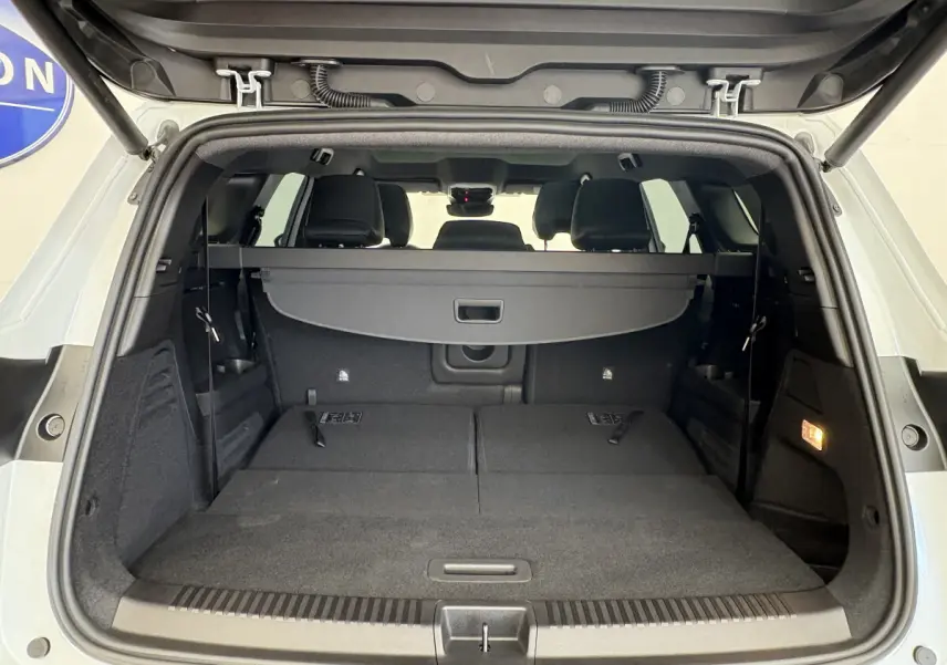 Coffre ouvert vu de l'arrière d'un Renault Espace blanc 2025 avec sièges rabattus et cache-bagages noir.