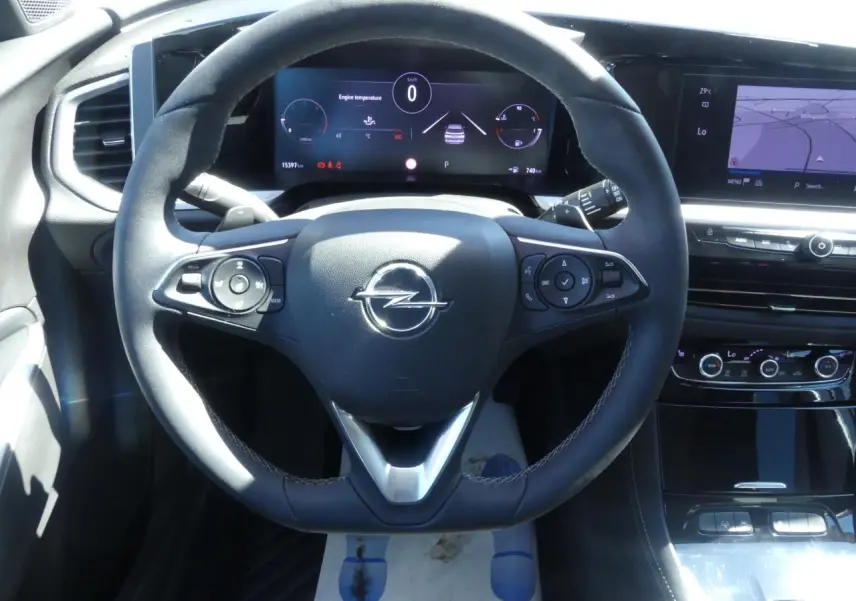 Vue intérieure centrée sur le volant noir de l'Opel Grandland 2024 avec tableau de bord numérique et écran tactile.