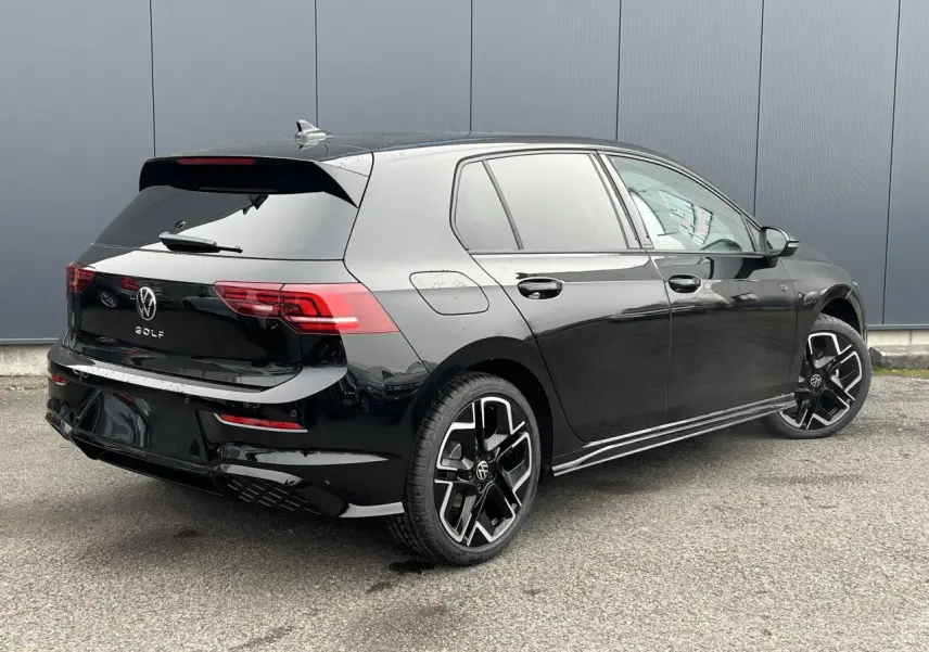 Vue 3/4 arrière droite d'une Volkswagen Golf VIII noire avec jantes alliage 18 pouces et toit ouvrant panoramique.
