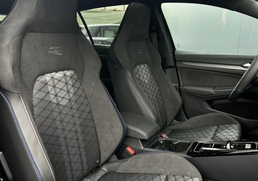 Vue intérieure côté droit montrant les sièges sport R-Line en alcantara gris avec surpiqûres bleues et motifs géométriques.