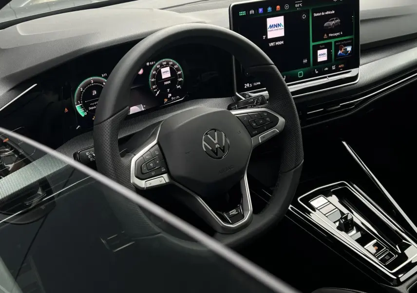 Vue intérieure centrée sur le volant multifonctions et le tableau de bord numérique de la Volkswagen Golf VIII noire.