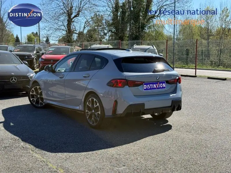 BMW Série 1 120dA M Sport en M Brooklyn Grey, vue 3/4 arrière droit, avec jantes alu et feux LED arrière.