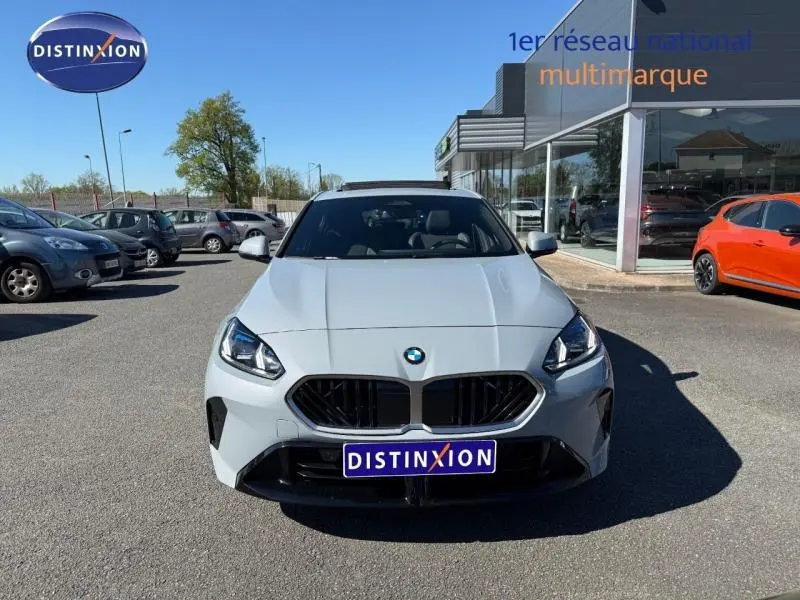 Vue avant d'une BMW Série 1 120dA M Sport en gris Brooklyn métallisé, avec calandre noire et phares LED allumés.