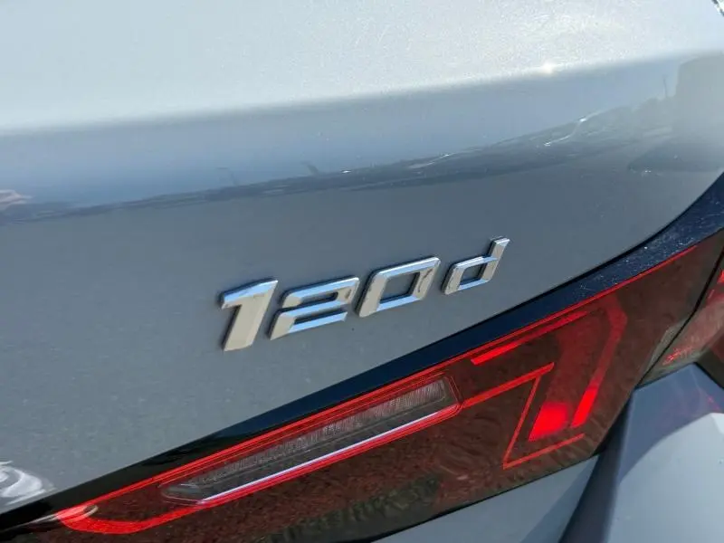 Gros plan sur l'arrière droit d'une BMW Série 1 120d en gris métallisé, avec le badge "120d" et un feu arrière LED rouge.