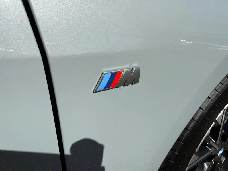 Gros plan sur l'emblème M sur la portière côté gauche d'une BMW Série 1 gris Brooklyn métallisé.