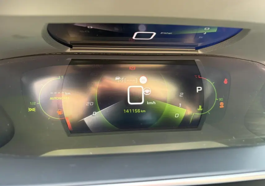 Vue rapprochée du combiné numérique 3D du tableau de bord du Peugeot 2008 noir, affichant 141156 km et indicateurs verts et rouges.