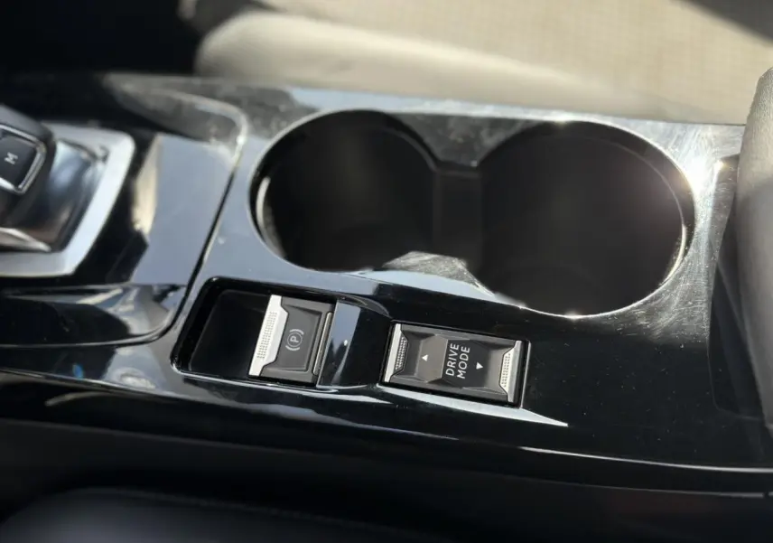 Gros plan sur la console centrale noire brillante du Peugeot 2008 GT 2021, avec boutons frein électrique et mode de conduite.