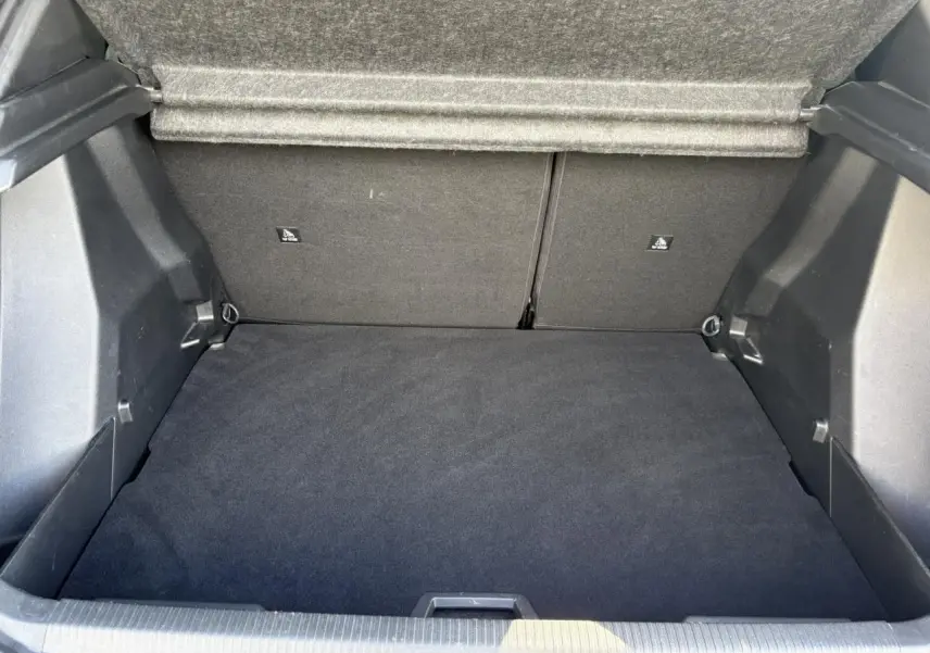 Coffre ouvert vu de face, intérieur noir avec tapis de sol et banquette arrière rabattable du Peugeot 2008 Noir Onyx.