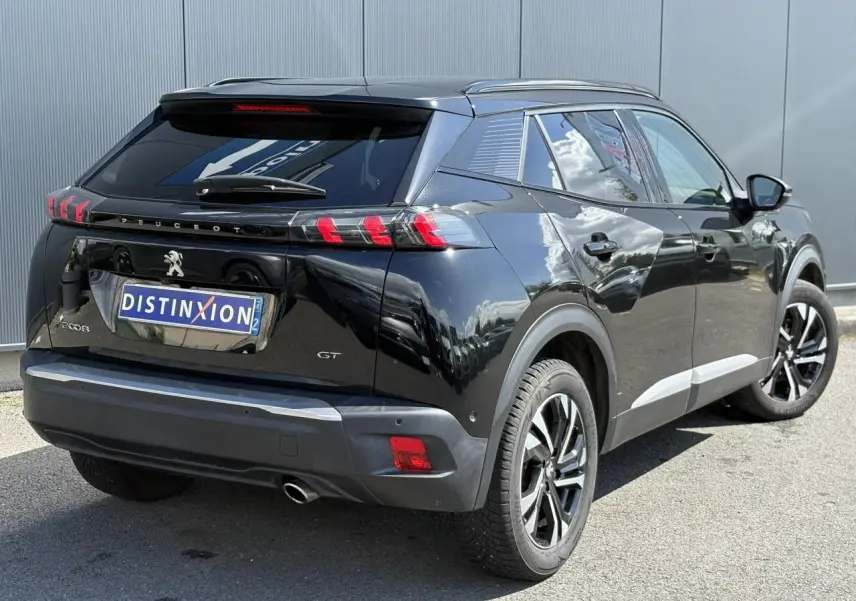 Vue 3/4 arrière droite d’un Peugeot 2008 GT noir Onyx avec feux arrière LED en forme de griffes et jantes alliage bi-ton.