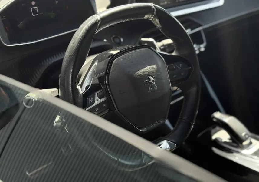 Vue rapprochée du volant cuir noir du Peugeot 2008 GT 2021 avec commandes intégrées et console de boîte automatique.