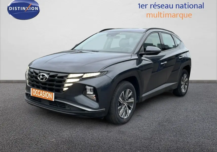 Vue 3/4 avant d'un Hyundai Tucson 2023 hybride en Dark Knight Metal avec calandre distinctive et jantes alliage.