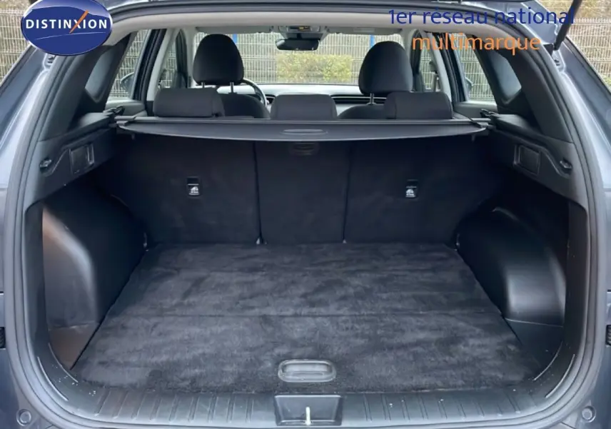 Coffre ouvert vu de l'arrière d'un Hyundai Tucson 2023 Dark Knight Metal, intérieur noir avec cache-bagages déployé.